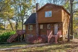 A large brown two-story cabin is nestled in the woods of the Blue Ridge Mountains at Love Ridge Mountain Lodging in VA. This larger house rental is ideal for families or groups of friends seeking a nature-inspired getaway.